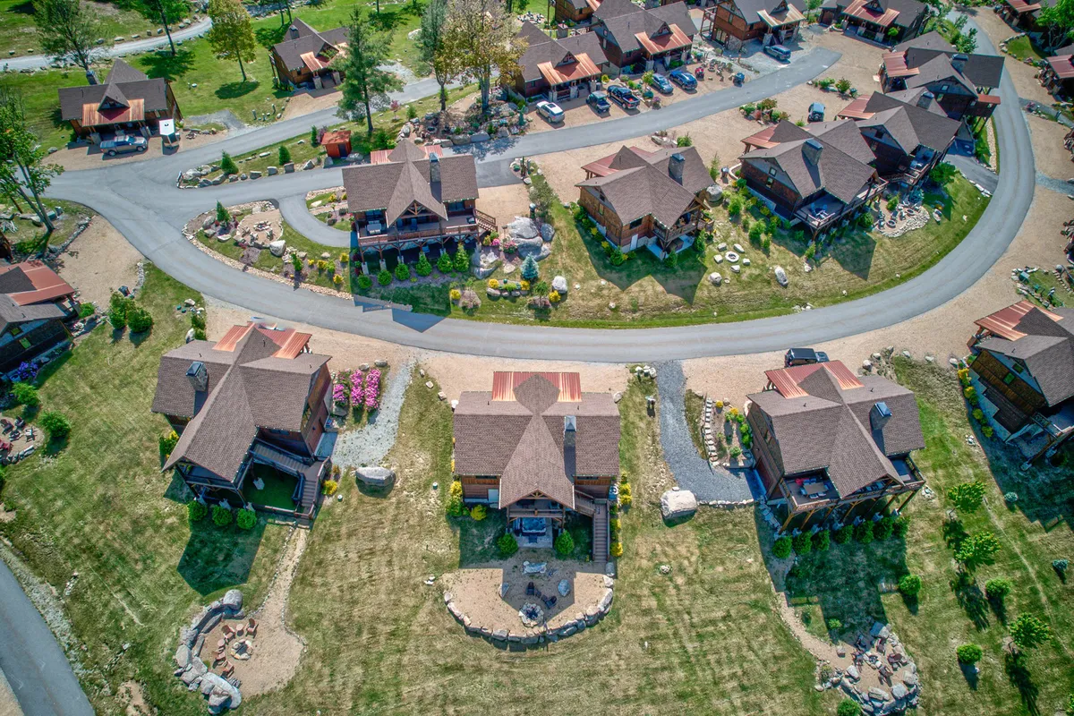 This image captures vibrant flower beds, well-maintained lawns, and charming cottages connected by curved roadways. It conveys an active, communal atmosphere with spaces ideal for walking, gardening, casual outdoor gatherings, and family picnics.