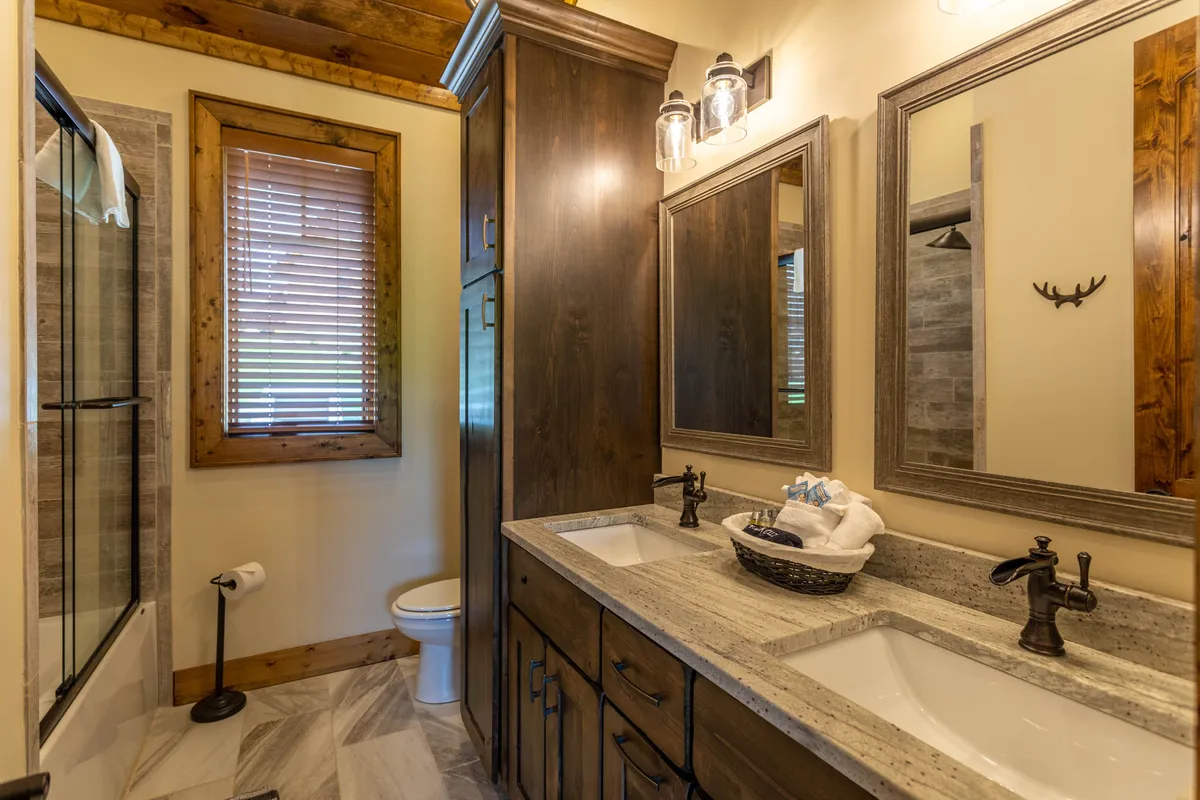 A second bathroom view with a double sink vanity, framed mirrors, wooden cabinetry, and a spacious shower area. The serene and clean design offers ample space for personal grooming and relaxation.