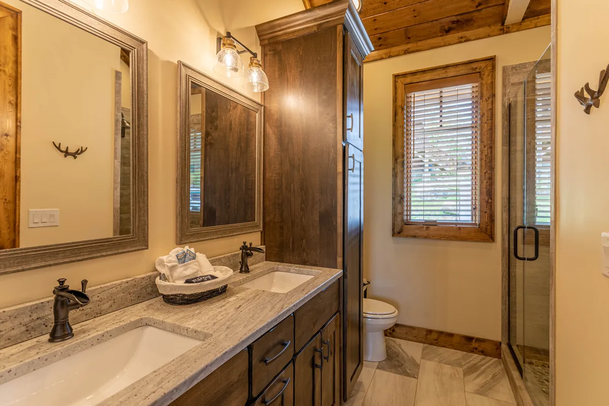 A spa-inspired bathroom with a double vanity sink, large mirrors, natural wood accents, and a glass-enclosed walk-in shower. The design is both modern and calming, emphasizing relaxation and self-care.